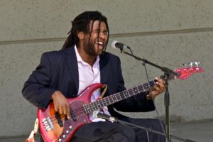 bearded, wearing a suit, singing playing bass